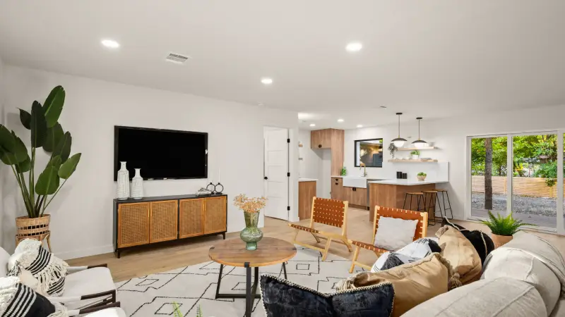 Remodeled family room in celing lights with an L shaped couch and two chairs creating a sectioned area facing a mounted flat screen television