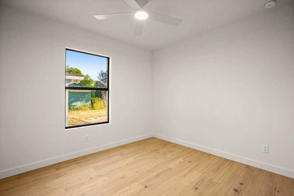 Bedroom with window, flooring, and ceiling fan.