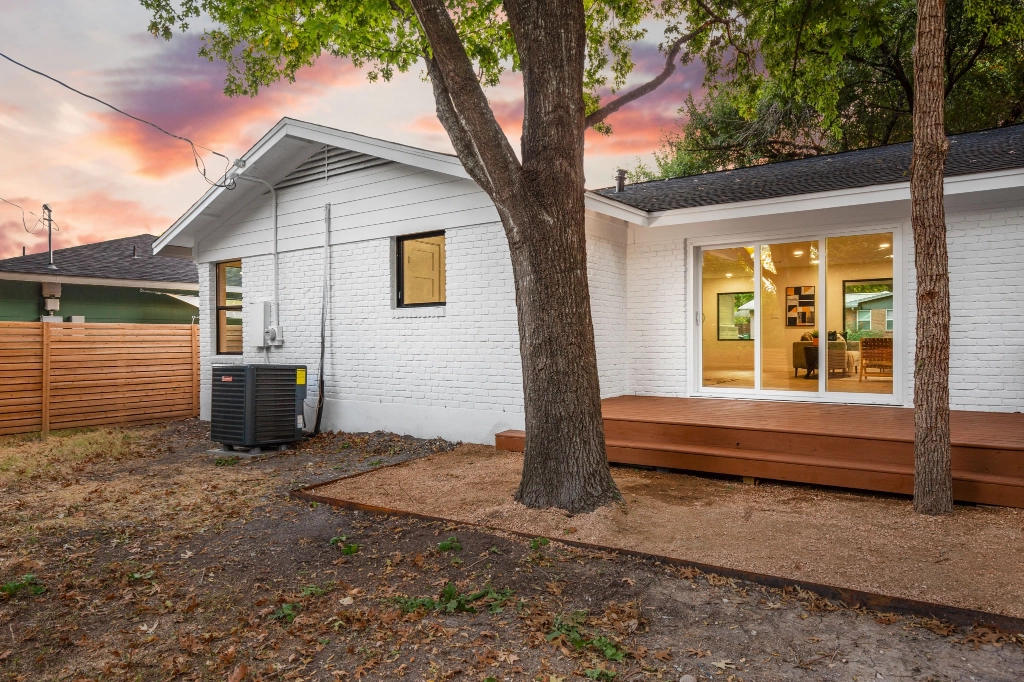 Exterior view of back of home showing a deck and ac unit.