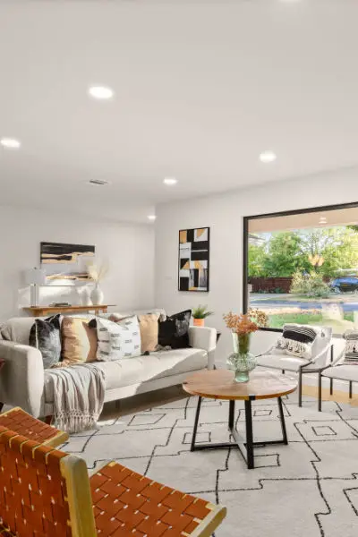 a remodeled living room with couch, chairs, and center table.